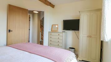 A bedroom with a bed, a wardrobe, a television, and a door leading to another room.