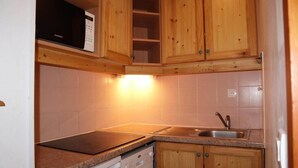A kitchen with wooden cabinets, a microwave, a dishwasher, and a sink. - 100m from resort center, 1st floor, swimming pool, sauna, balcony, tv, ski locker, 35m², Les Orres (Les Orres)