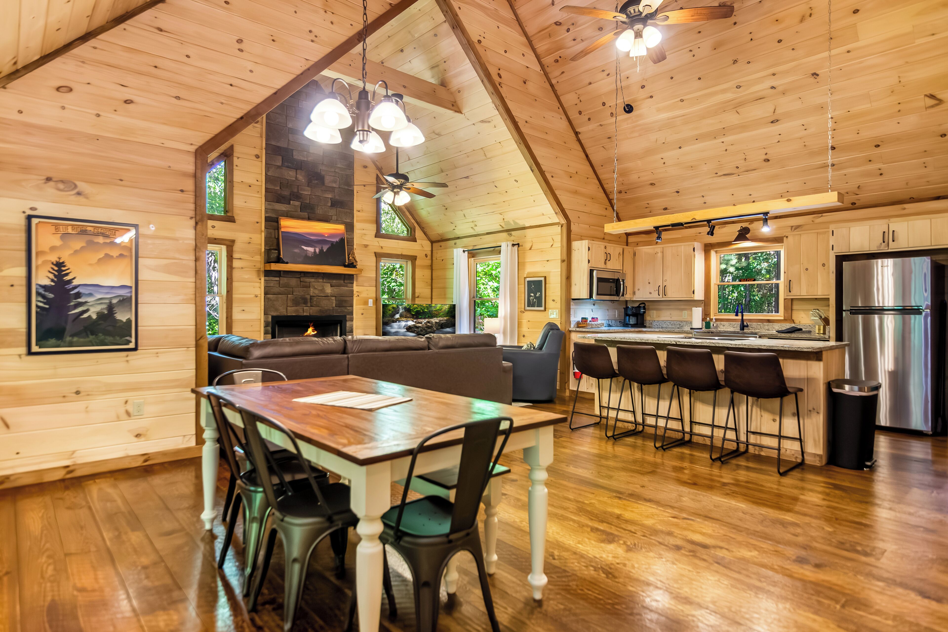 A wooden cabin interior with a dining area, kitchen, and seating.