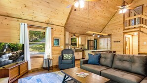 A wooden cabin interior with a living room, kitchen, and balcony. - Spacious, New Cabin! New Hot Tub, Fire Pit, and Game Room! Dog-Friendly! (Blue Ridge)