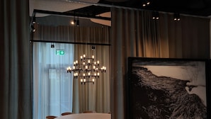 Un comedor moderno con una mesa redonda, sillas, una araña y un cuadro abstracto grande en la pared.