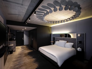 A modern hotel room with a large bed, a ceiling with a unique light fixture, and a wall-mounted TV.