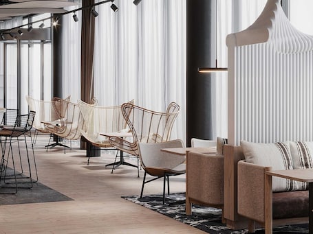 Ein modernes Interieur mit Korbstühlen, einer Couch und einem Essbereich.. Mercure Hotel Delémont