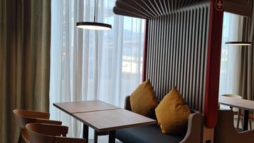 Un interior moderno con zona de comedor, sofá con cojines y alfombra estampada.