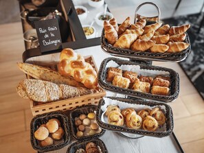 A variety of baked goods including bread, croissants, and pastries displayed in baskets and on a tray. - Mercure Hotel Delémont (Delemont)