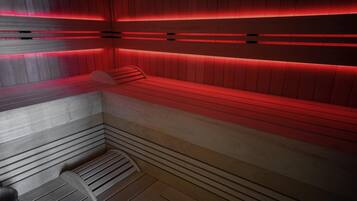 Un sauna avec des bancs en bois et un éclairage rouge.