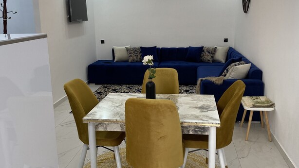 Un comedor moderno con una mesa de mármol, sillas color mostaza y una alfombra estampada.