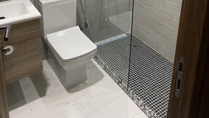 Un baño moderno con ducha envuelta en vidrio, inodoro blanco y lavamanos.