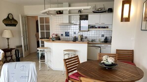 Eine moderne Küche mit weißen Schränken, einer zentralen Kochinsel und einem Essbereich mit Holztisch und Stühlen.