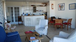 Ein kompakter Wohnraum mit Küchenzeile, Essbereich und Sitzecke mit Sofa und Sesseln.