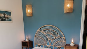 Ein Schlafzimmer mit einem Bett, zwei Nachttischen, einer Wandlampe und einem gerahmten Bild an der Wand.