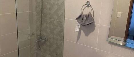 A modern bathroom with a glass-enclosed shower, a toilet, a sink, and a towel rack.