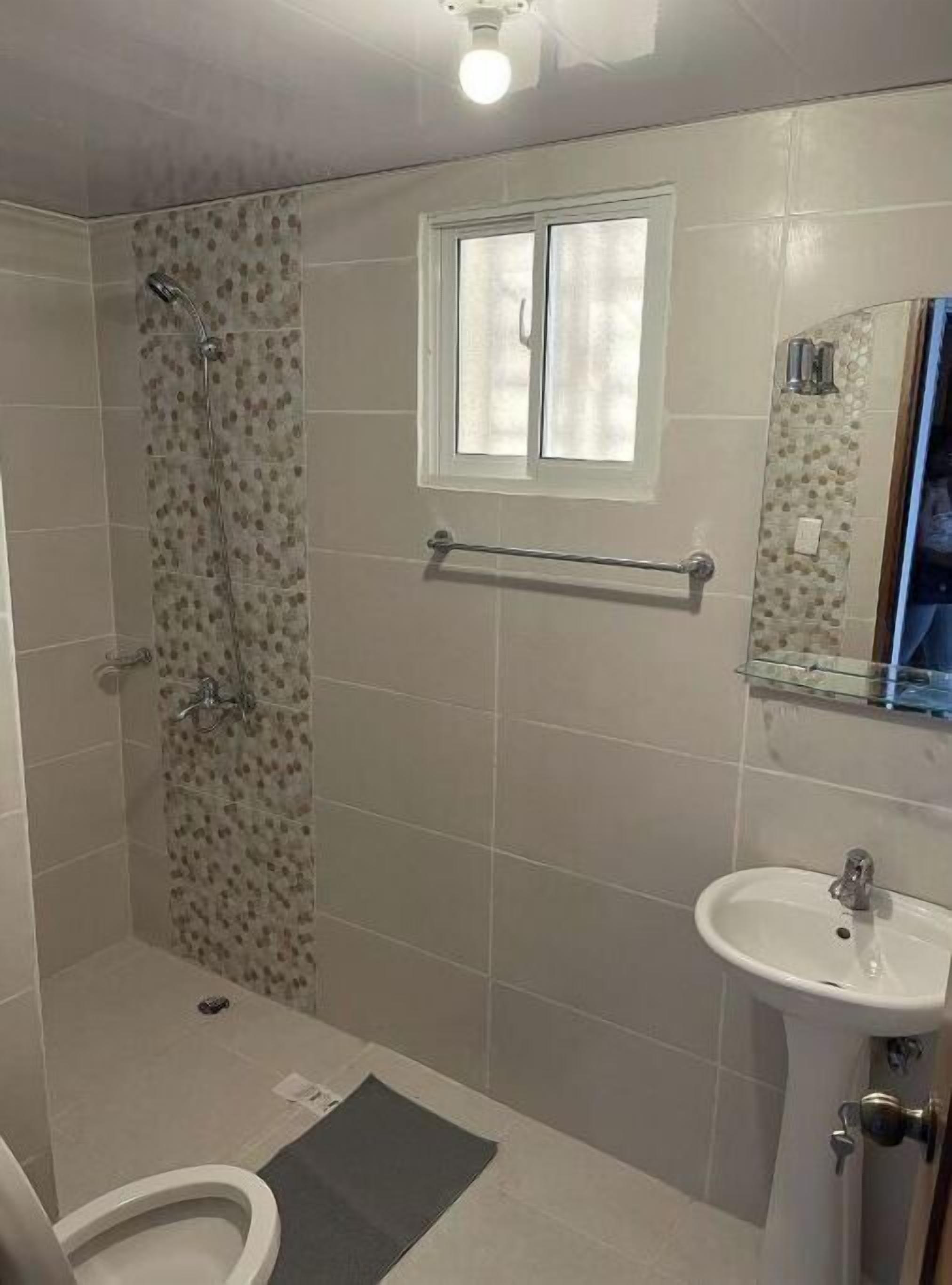 Baño con ducha, inodoro, lavabo y ventana.