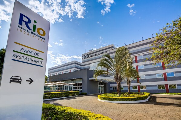 Una entrada de hotel moderna con un letrero que dice 'Rio Hotel by Bourbon Indaiatuba' y una flecha señalando a la derecha.