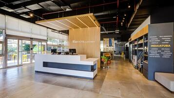 A modern hotel reception area with a wooden reception desk, a digital screen, and a seating area.