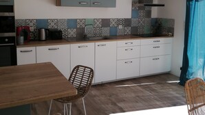 A modern kitchen with white cabinets, a wooden countertop, and a dining area with wicker chairs. - 4 Bedroom Private vacation home in Baden (Baden)