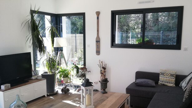 A modern living room with a flat-screen TV, a wooden coffee table, a grey sofa, and a large window with a view of greenery. - 4 Bedroom Private vacation home in Baden (Baden)