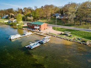 A lakeside property with a dock, a building with a green roof, and a grassy area with a pathway.