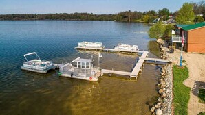 A lakeside dock with boats, a wooden pier, and a building with a green roof.