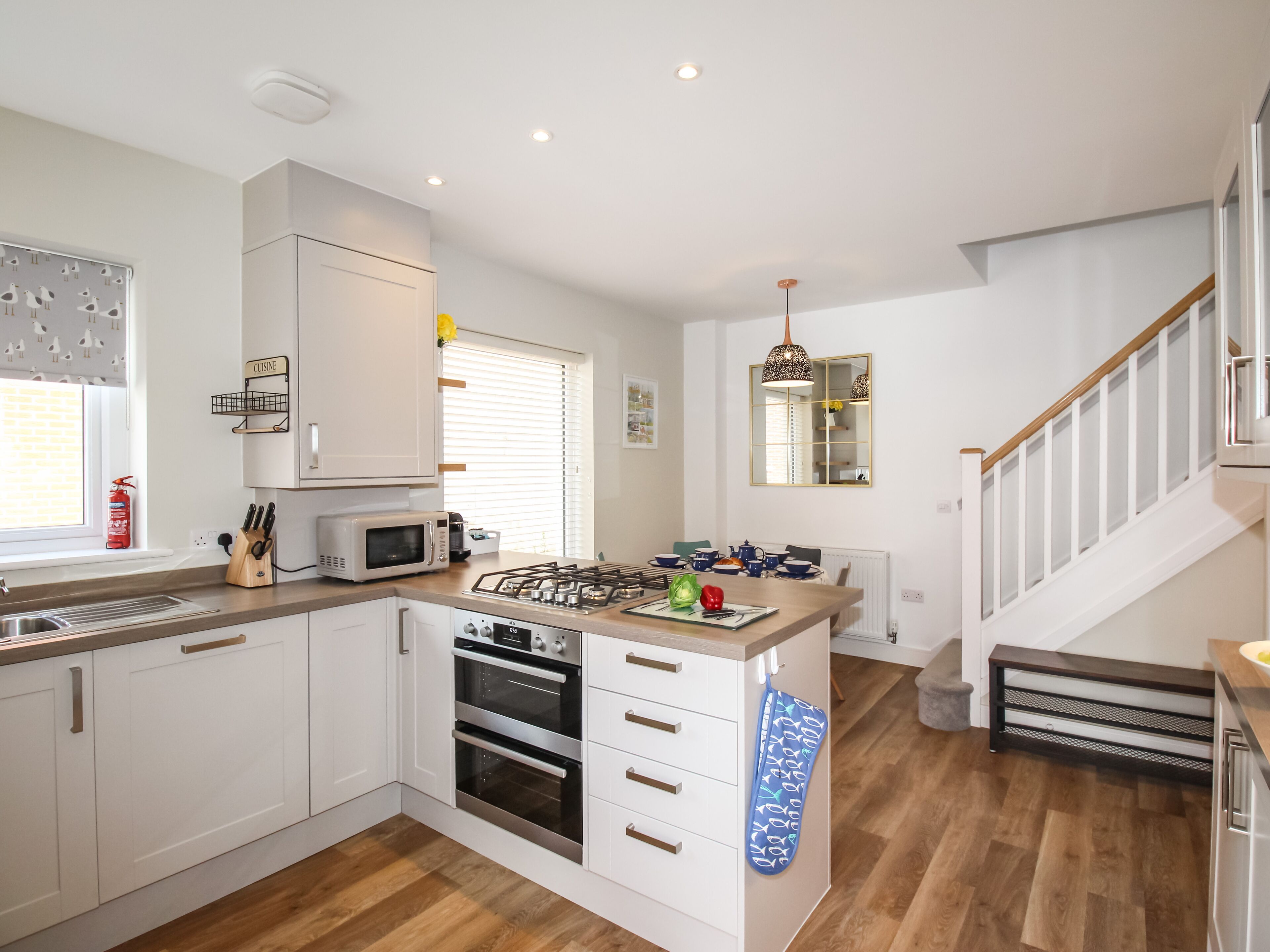 A modern kitchen with white cabinets, a built-in oven, a microwave, and a gas stove.