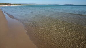 A beach with clear shallow waters and a sandy shore.