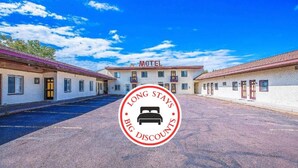 Een motel met een centraal gebouw met de tekst 'Motel' en een parkeerplaats ervoor.