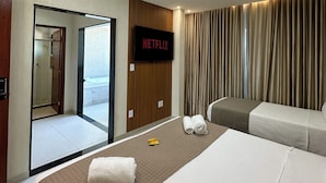 A hotel room with a bed, a TV mounted on the wall, a bathroom visible through an open door, and a view of the sea. -  Viver Pousada (Saquarema)