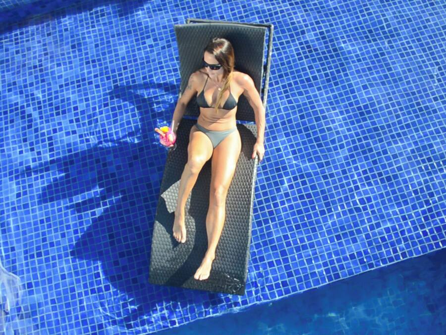 Eine Person sonnt sich auf einer Liege in einem Pool mit blauen Mosaikfliesen.