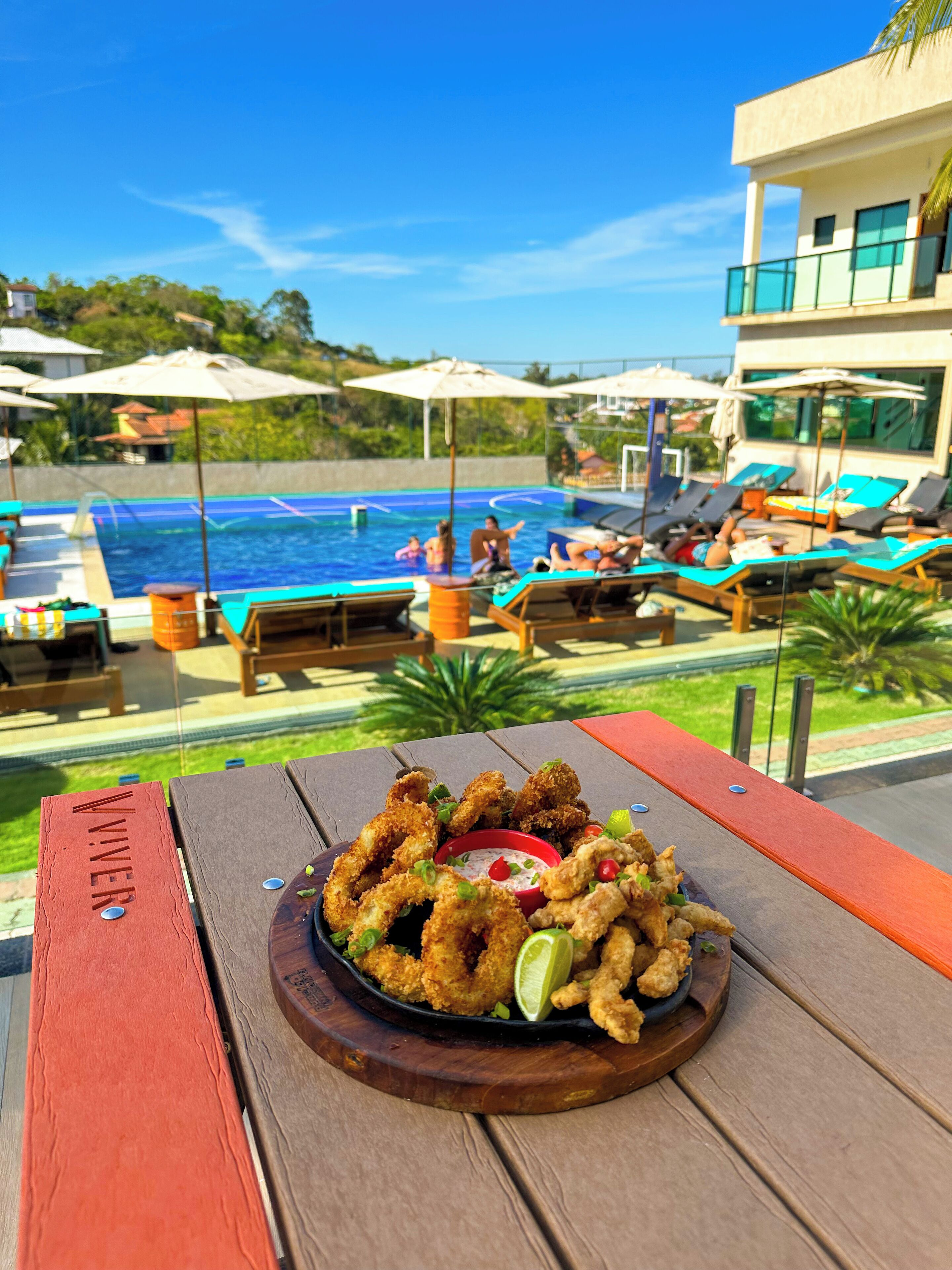 Vista a la piscina con una mesa de comedor que presenta mariscos fritos y vistas del área de la piscina.
