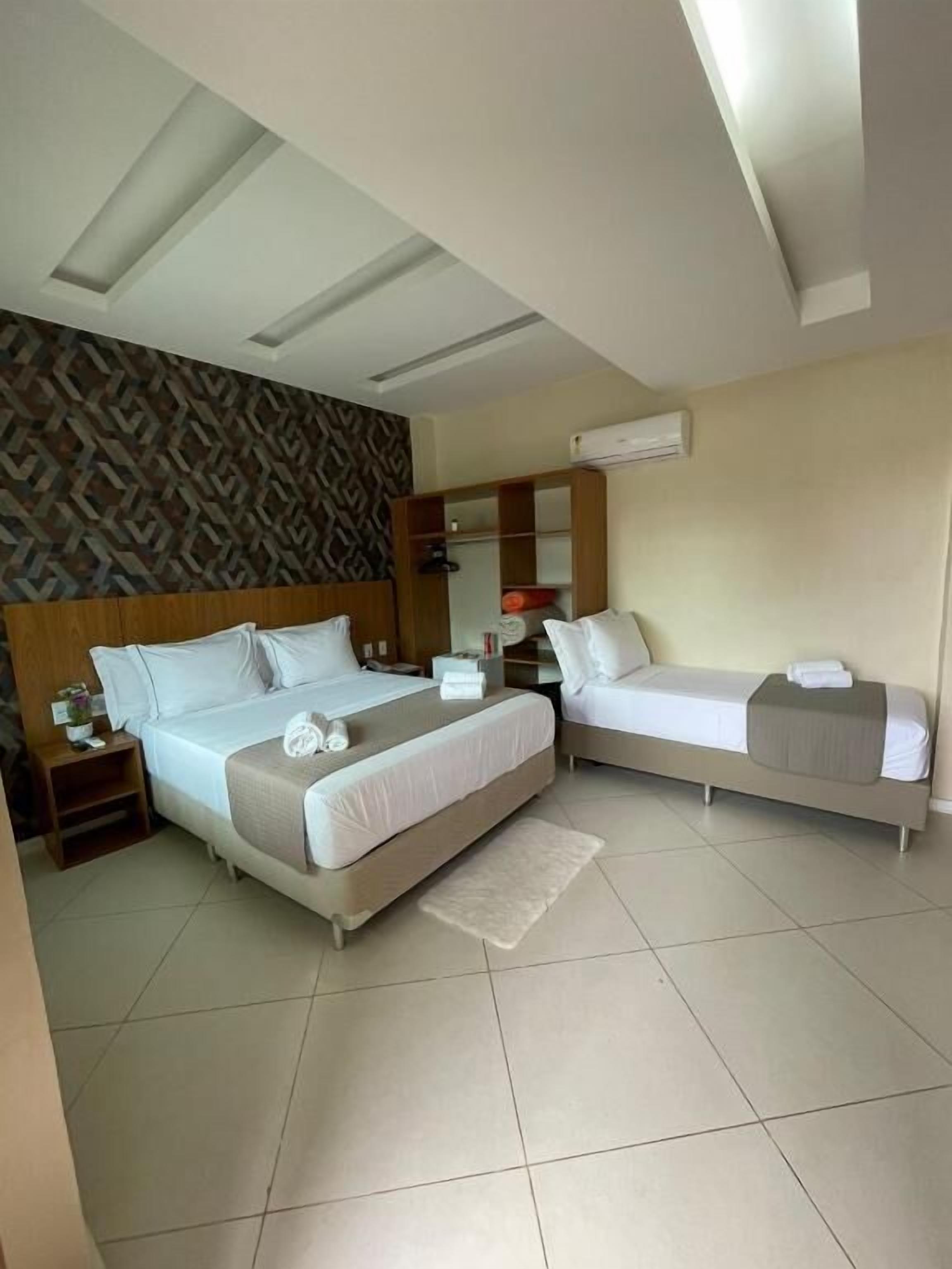 A hotel room with two beds, a patterned wall, and a built-in wardrobe.