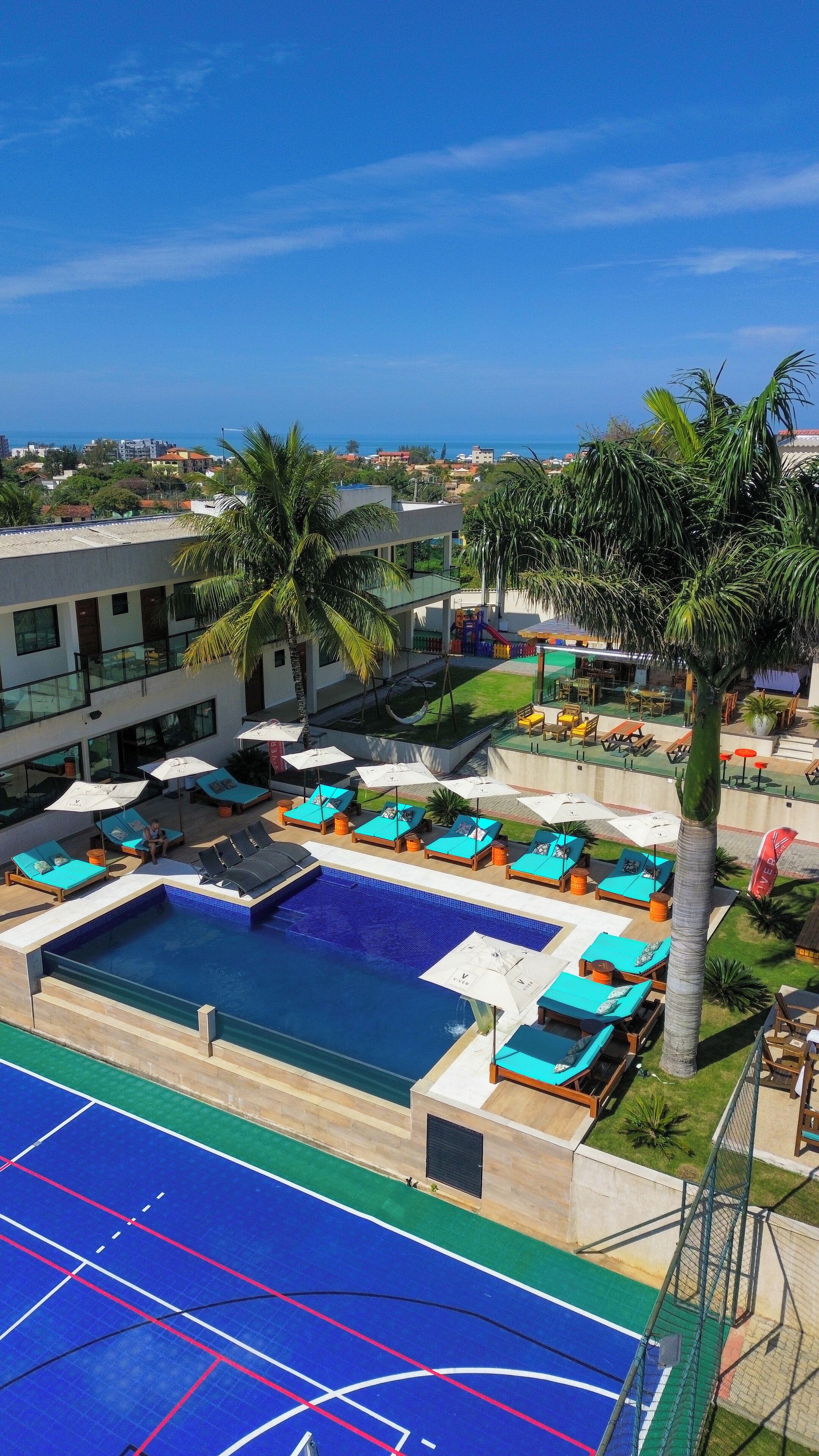 A pool area with sun loungers and a basketball court.