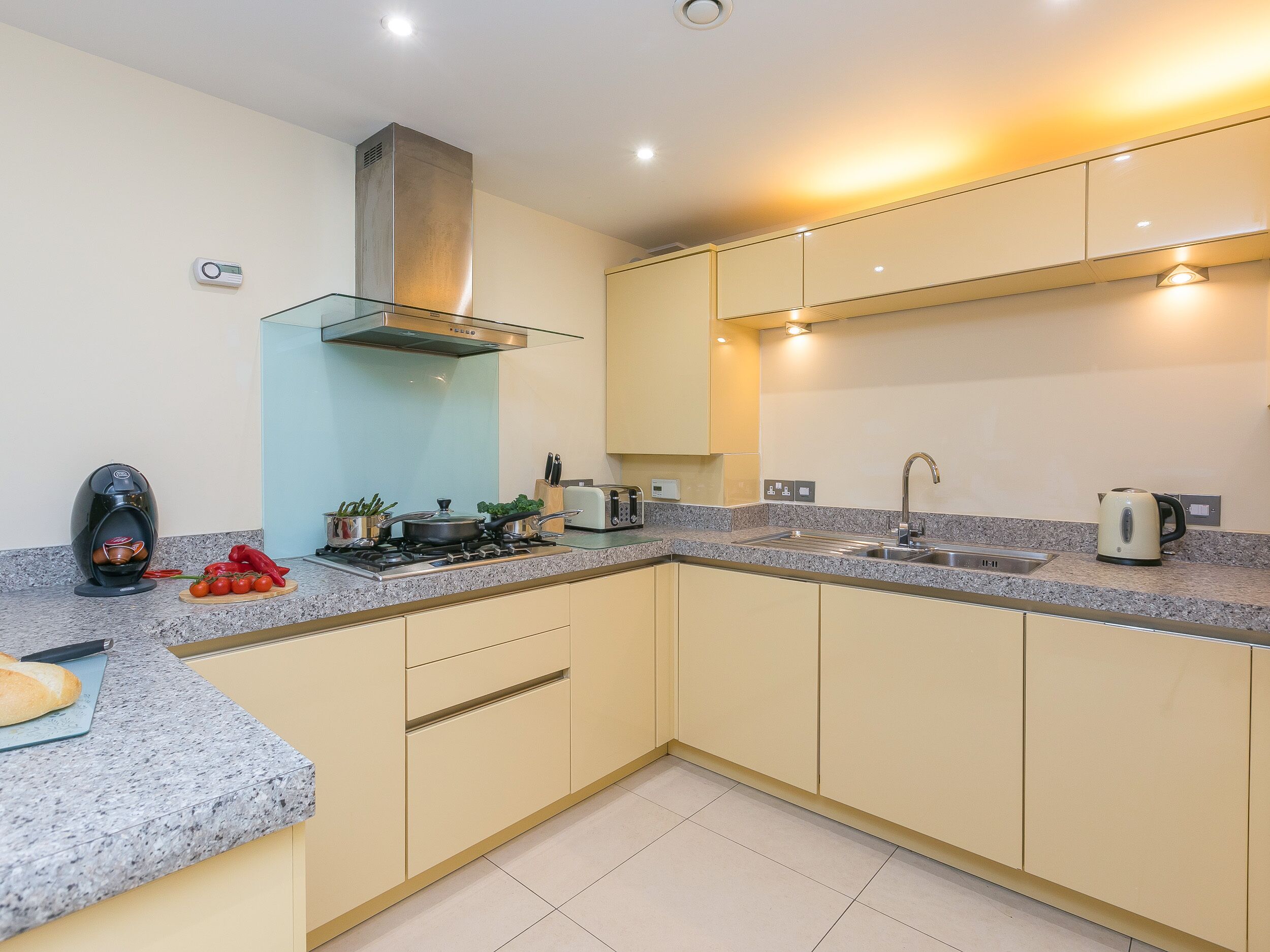 Una cocina moderna con encimeras de granito, electrodomésticos de acero inoxidable y armarios color beige.