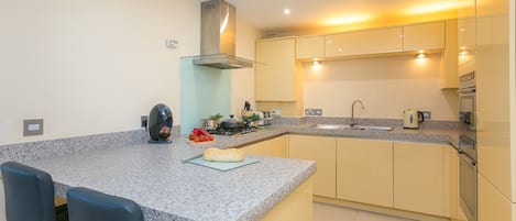 A modern kitchen with granite countertops, stainless steel appliances, and a central island with bar stools.