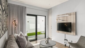 Una sala de estar moderna con un sofá gris, una mesa de centro y un televisor de pantalla plana montado en la pared.