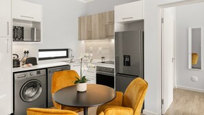 Cocina compacta con electrodomésticos modernos, lavadora y comedor con mesa y sillas.