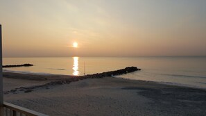 Eine Strandansicht mit blauem Himmel, ruhiger See und Felsformationen.