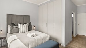 Ein modernes Schlafzimmer mit einem großen Bett, einem Kleiderschrank und einem Nachttisch mit Lampe.