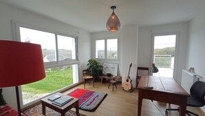 A spacious living room with large windows, a wooden table, a red lamp, and a guitar. - House between Morgat beach (2km) and Crozon town (1km). (Crozon)