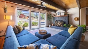 Ein gemütliches Wohnzimmer mit einem blauen Sofa, einem Kamin und Blick ins Freie.