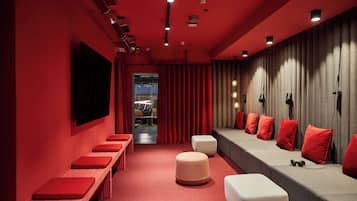 A red-themed room with a long bench, ottomans, and a sofa with red cushions.