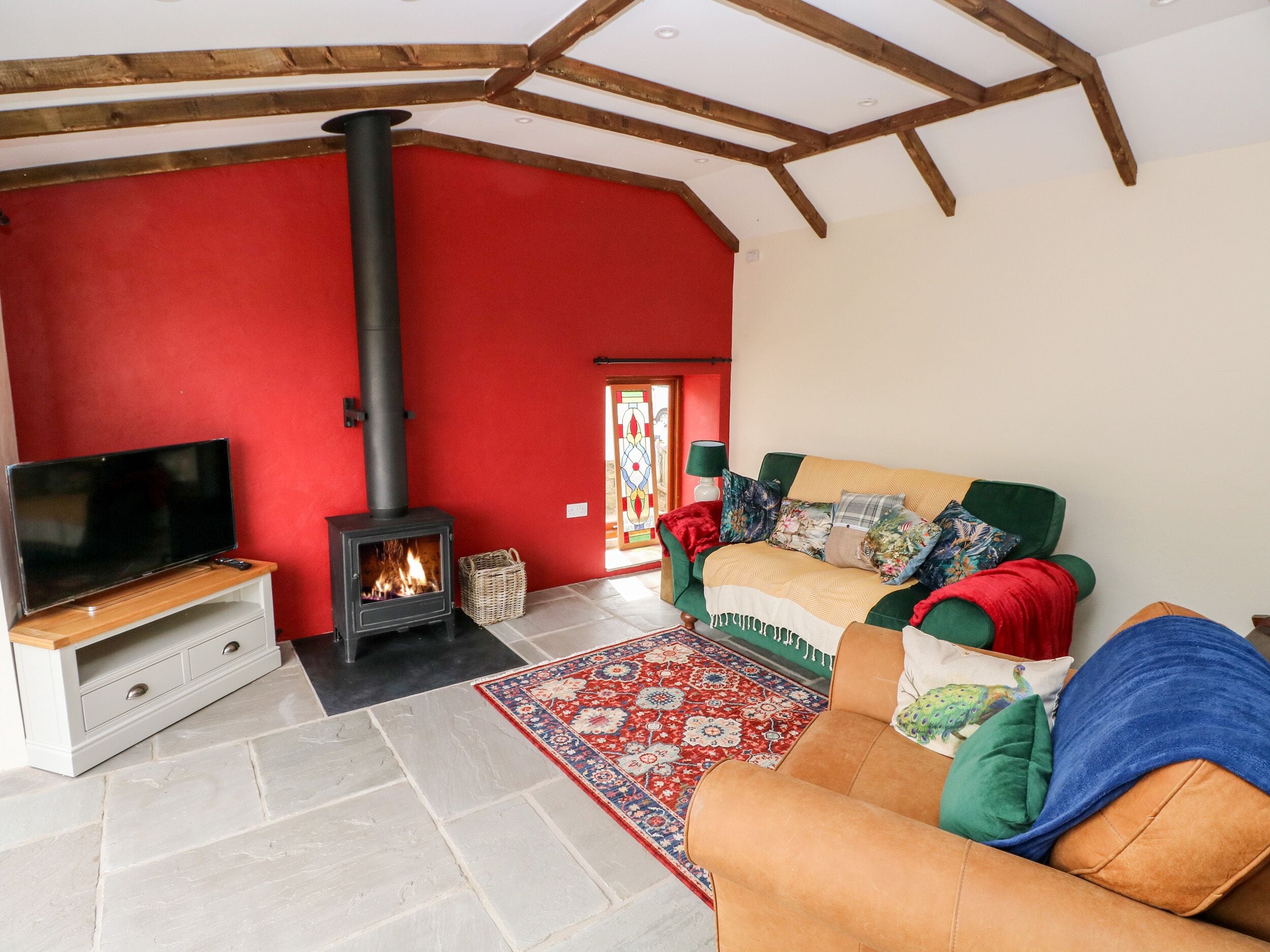 A living room with a TV, a fireplace, a sofa, and a patterned rug.