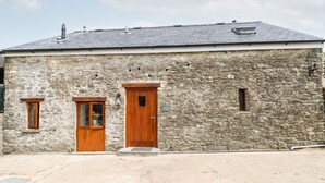 A stone building with two wooden doors and a small window. - Lime Kiln Cottage (Bridgend)