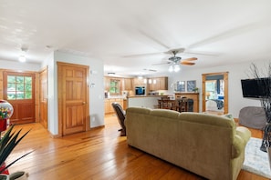 A spacious living area with a wooden floor, a beige sofa, and a ceiling fan. - Hidden Gem: Upscale Area, EV Charger, Firepit, Near HWY65 and I44 (Springfield)
