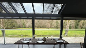 An outdoor dining area with a table set for four, overlooking a grassy field. - Primrose (Bodmin)