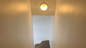 A wooden staircase with white walls and a ceiling light.