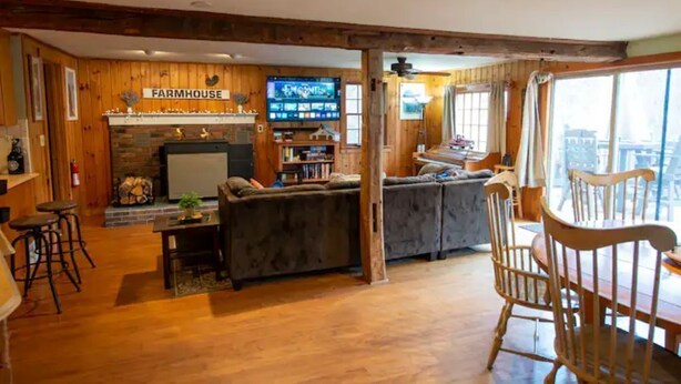A rustic interior with a fireplace, a television, and wooden furniture. - Village Home with 15 acre backyard on the river (Cavendish)
