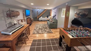 A cozy living room with a foosball table, a piano, and a television. - Village Home with 15 acre backyard on the river (Cavendish)