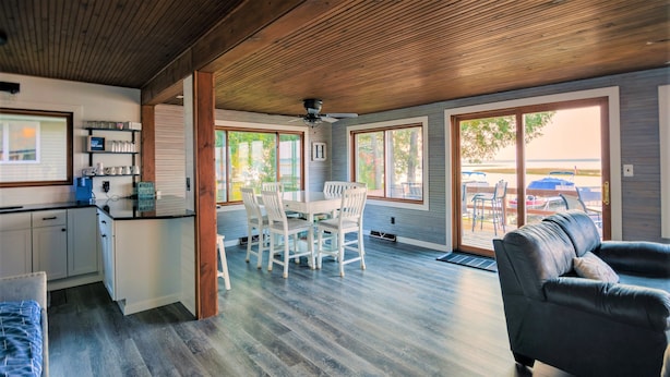 A spacious living area with a dining table and chairs, a sofa, and a kitchen area with cabinets and a coffee machine.