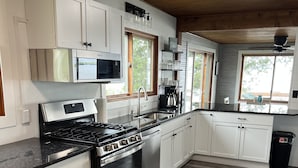 A modern kitchen with white cabinets, stainless steel appliances, and a wooden floor.