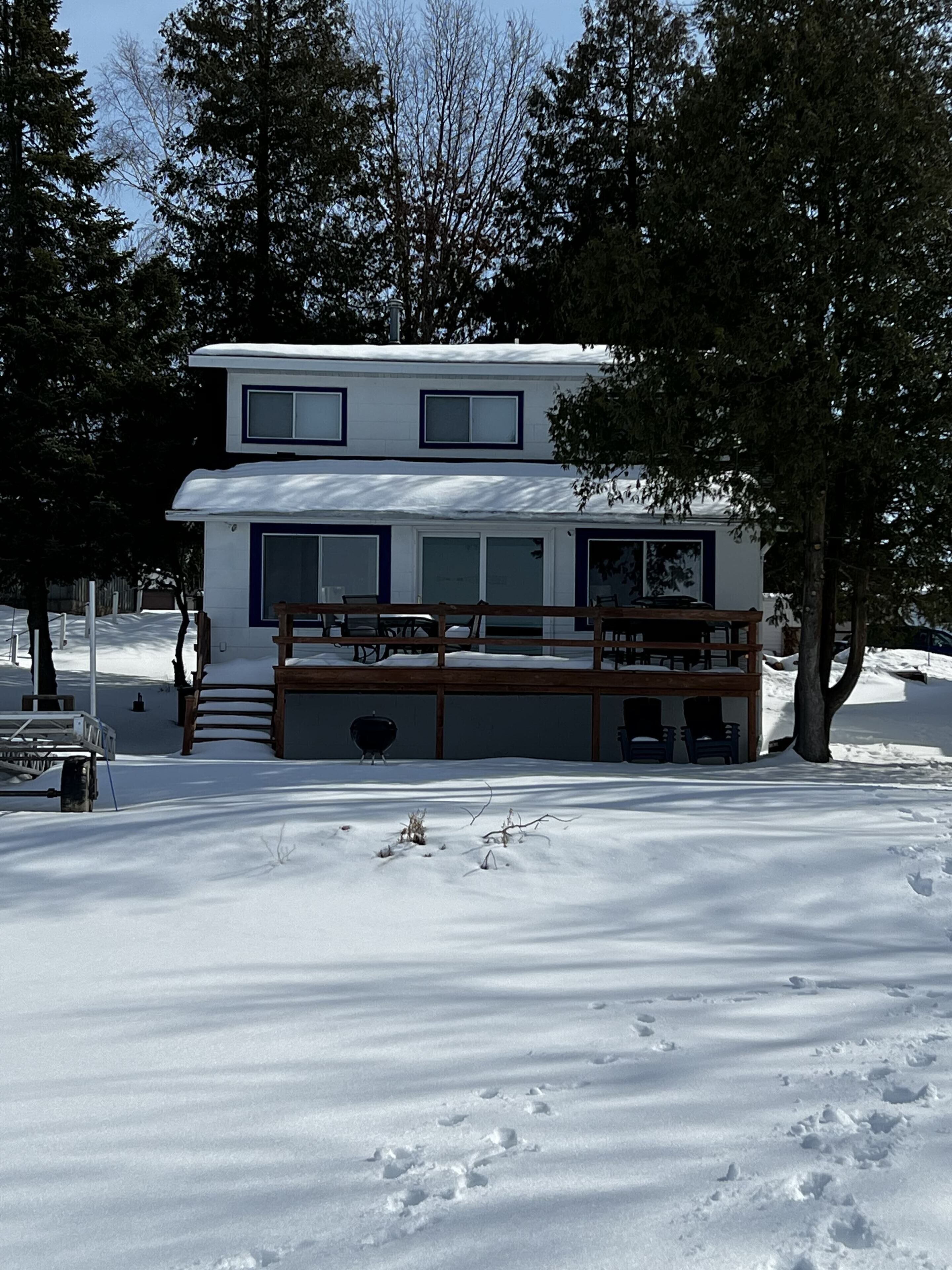 A two-story building with a covered deck and a snow-covered ground.